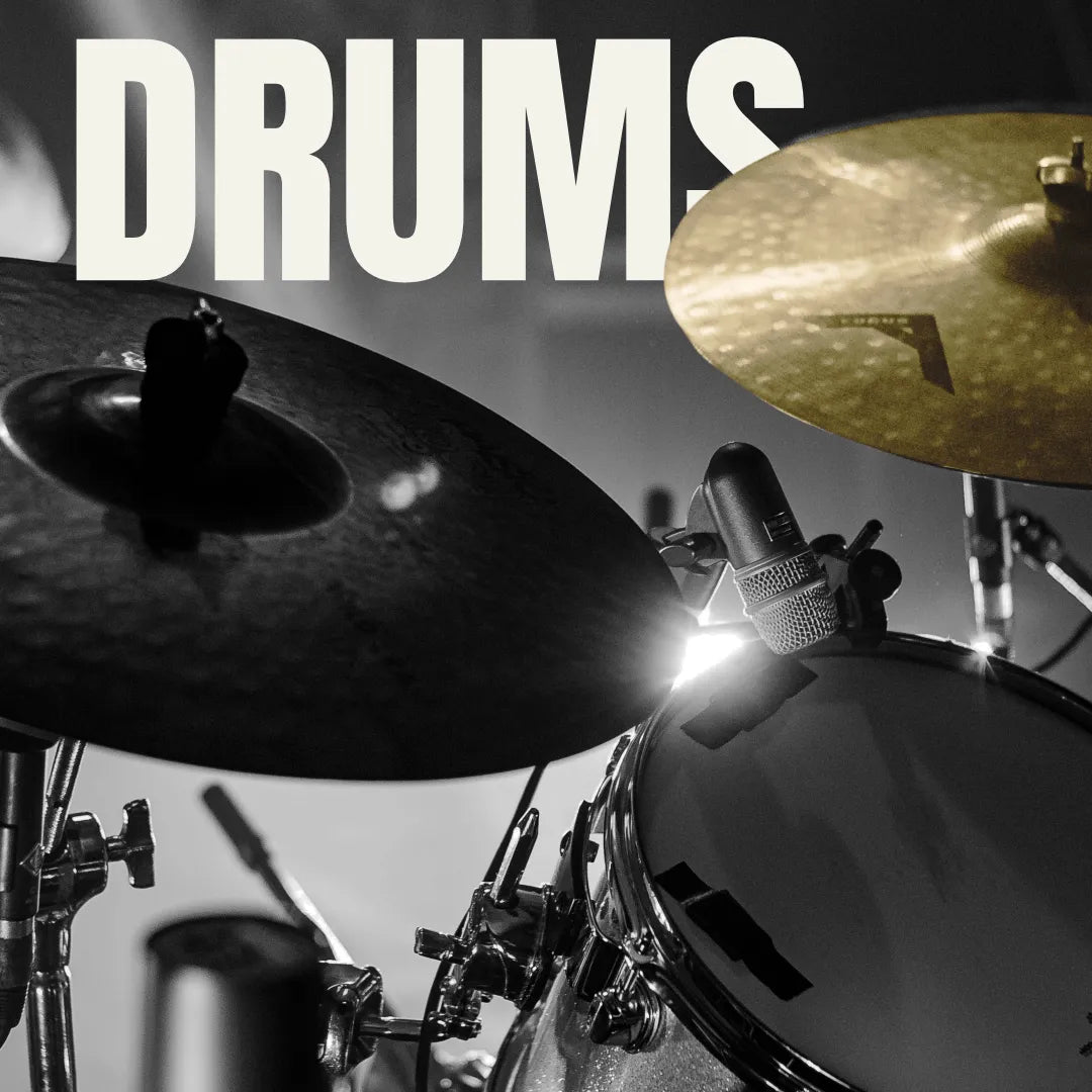 Close-up of a drum kit with a gold cymbal and microphone, set against a moody, high-contrast black and white background.