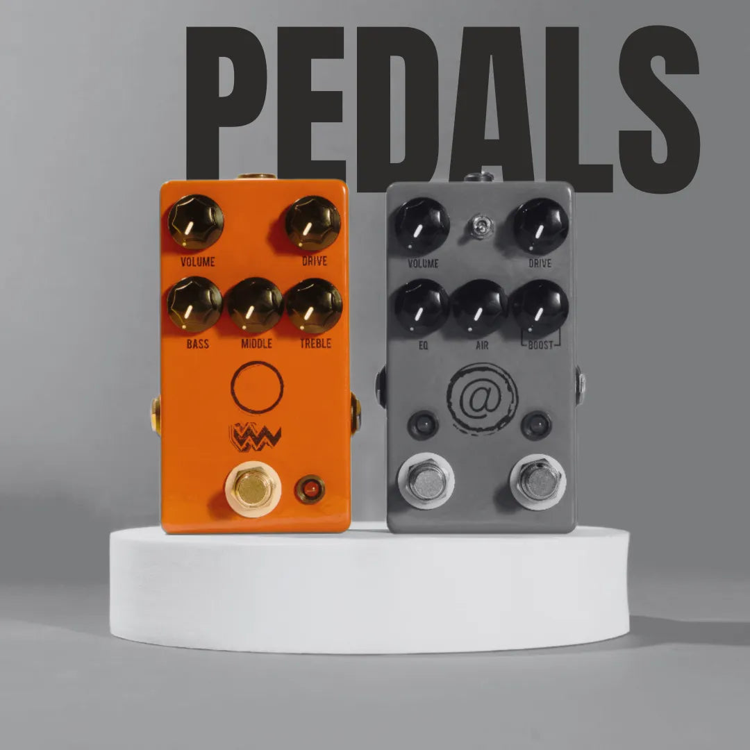 Orange and grey guitar effect pedals with black knobs displayed on a white circular pedestal against a grey background.