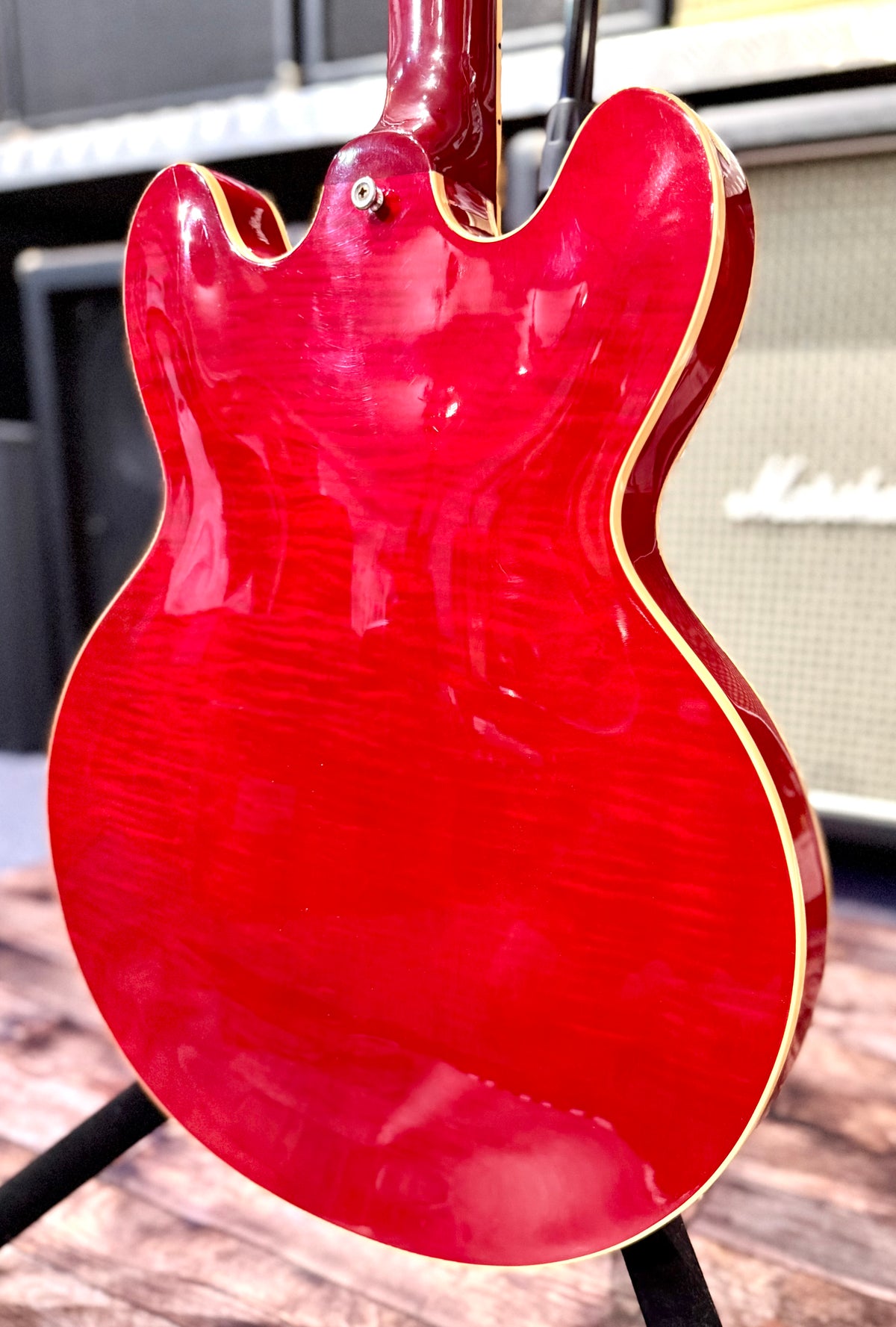 Angled view of the back of the body showing the bound edge and the curl of the flamed maple veneer under the light.