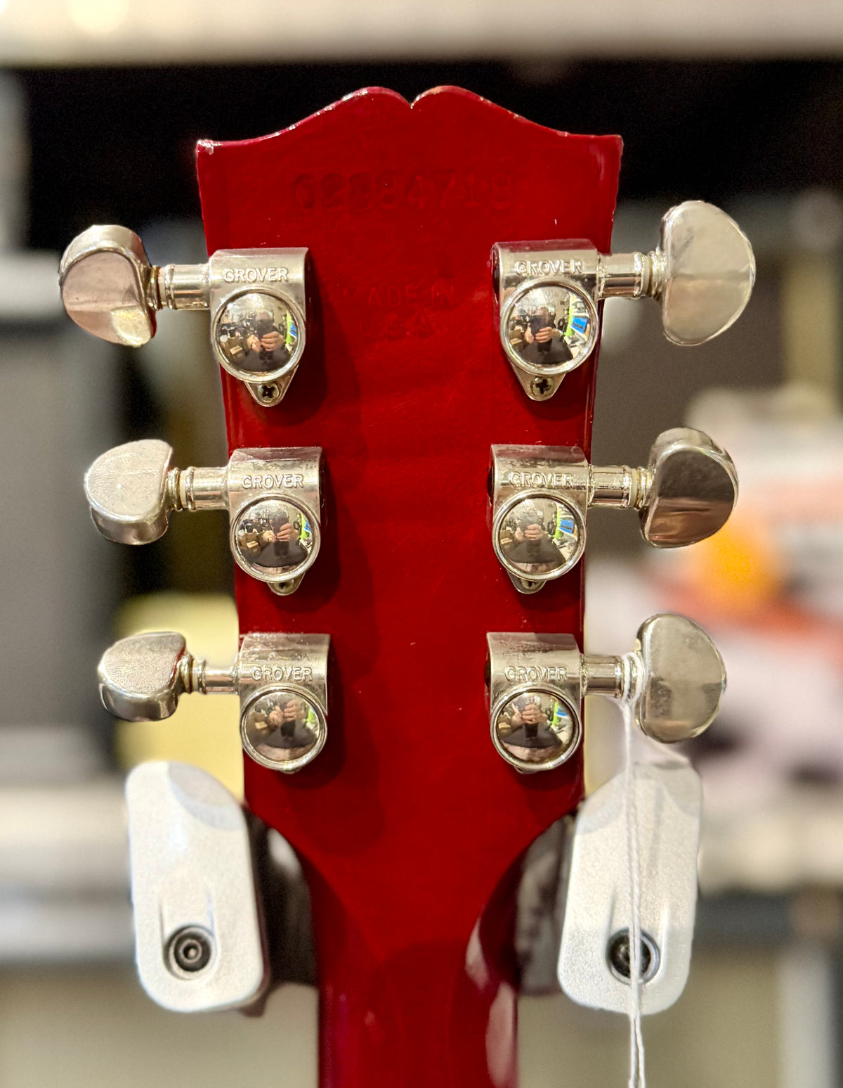 Back of the headstock in cherry red with Grover tuners and the factory serial number and Made In USA stamp impressed into the wood.