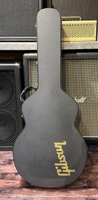 The included black Gibson hardshell case, closed, with a gold Gibson logo printed on the lower bout.