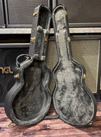 The hardshell case stood open on its end and empty, showing its grey plush lining and gold-tone hardware.