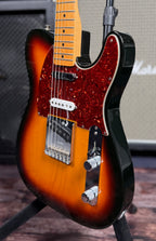 Three-quarter angled view showing the body's sunburst grading, the bound edge and the bridge with FENDER stamped bridge plate.