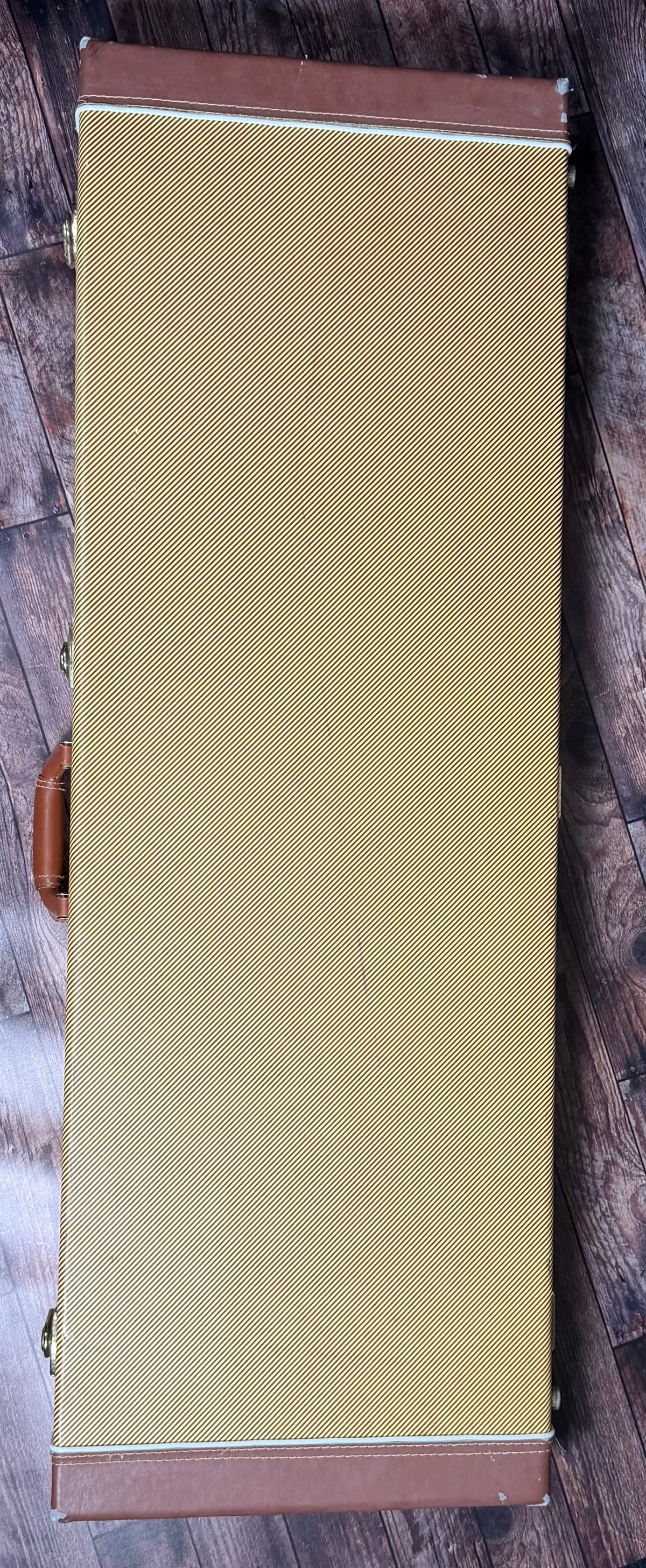 The included Fender tweed hard case, shown closed with its brown leather trim and handle.
