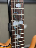 Close-up further down the fretboard showing a pair of pearl rose inlays where the neck meets the body.