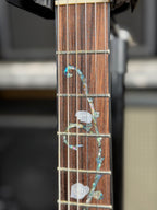 Extreme close-up of the rosewood fretboard showing the fine detail of the abalone vine and pearl rose inlay at the first few frets.