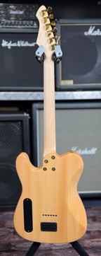 Full-length rear view of the guitar on its stand, showing the maple neck, headstock back and the body's battery compartment.