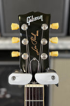 Straight-on close-up of the black headstock face showing the pearl Gibson logo, Les Paul Model script and cream tulip tuner buttons.