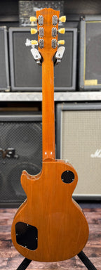 Full-length rear view showing the mahogany neck and headstock back, with the open-gear-style tuners and truss rod cover on the stand.