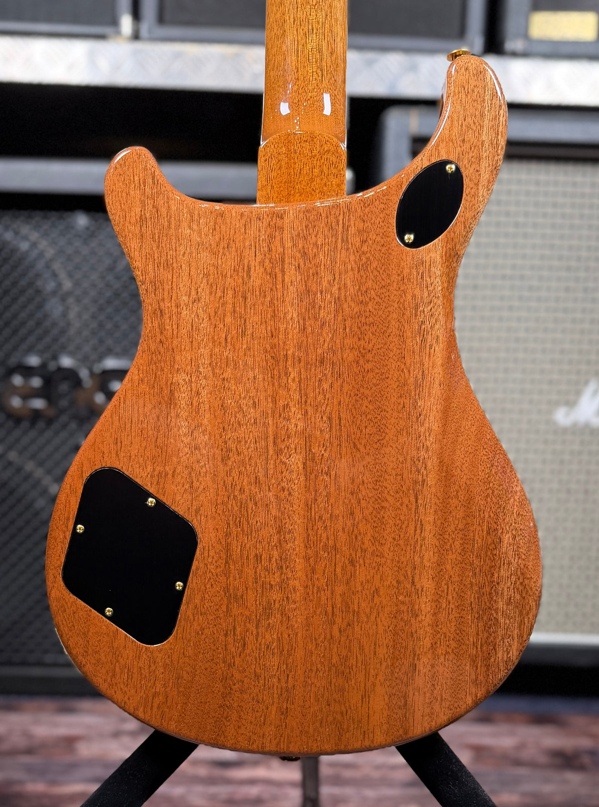 Full back of the guitar body showing the mahogany back grain, control cavity and access covers.