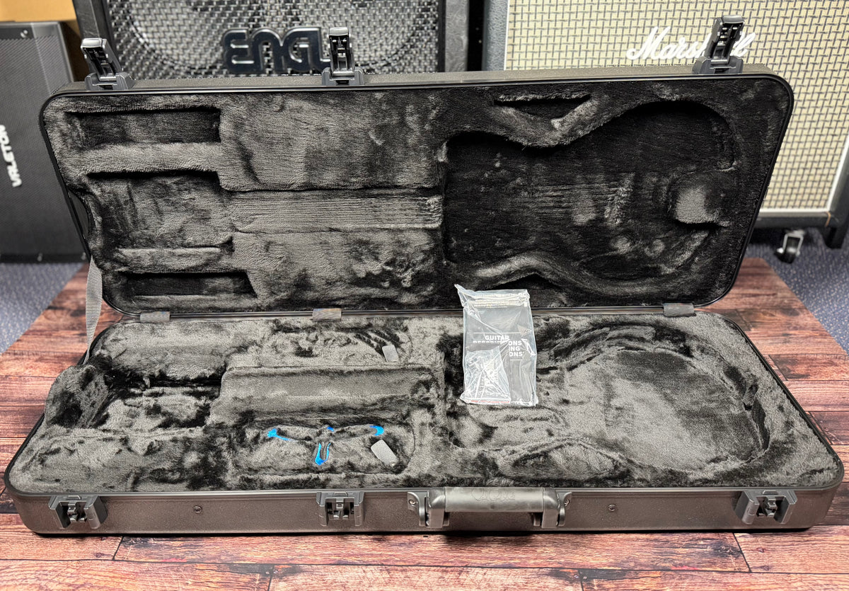 The case open and empty, showing the moulded grey plush interior and the PRS guitar documentation still in its plastic sleeve.