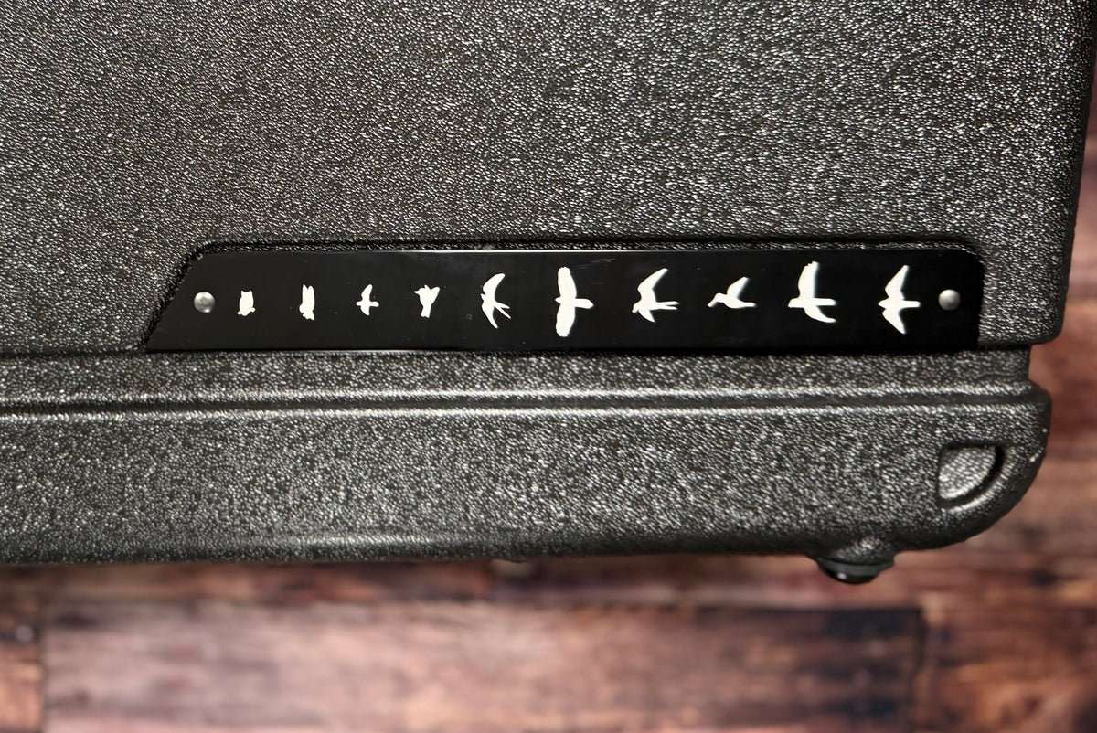 Close-up of the case's corner showing the PRS bird-in-flight logo plate on the textured case exterior.
