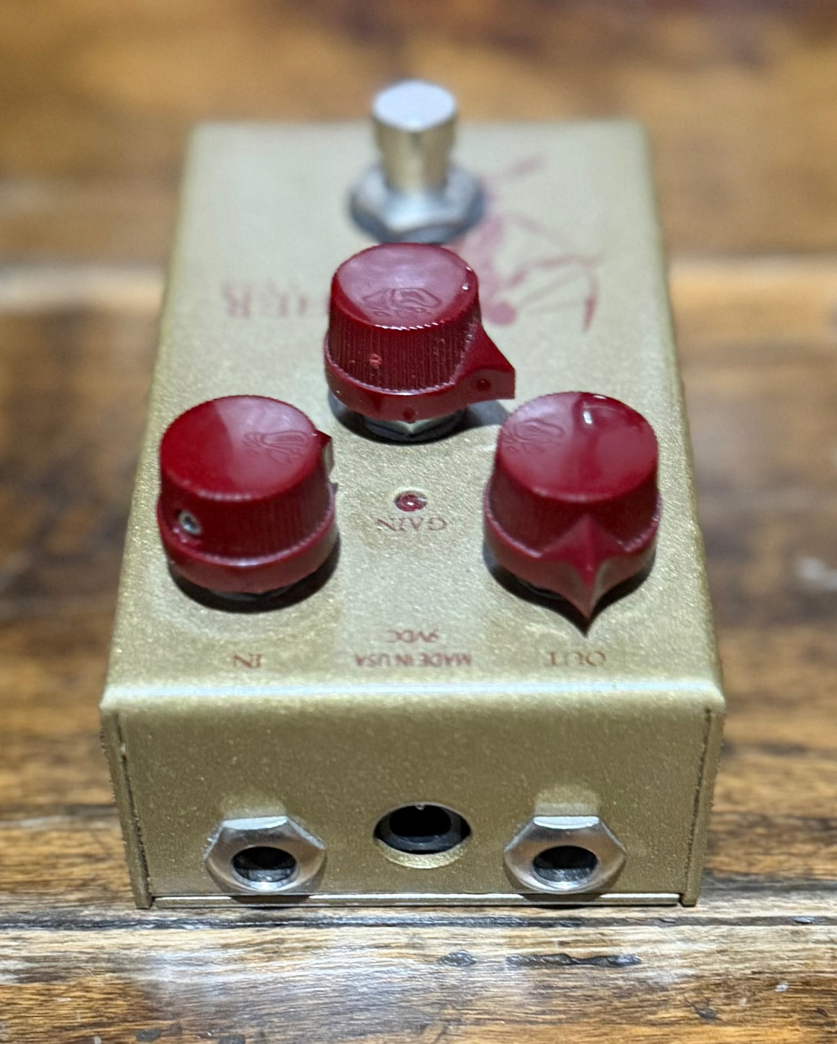 Upside-down view showing the IN and OUT jacks plus the centre DC power socket on the pedal's front edge.
