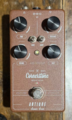 Top-down view of the Cornerstone Antique Classic Drive overdrive pedal in a brown textured enclosure, showing the Tone, Presence, Volume and Gain knobs, Mids and Comp toggle switches, status LED and footswitch on a wooden surface.
