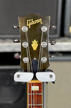Close-up of the front of the Gibson SG Deluxe headstock showing the Gibson logo and crown inlay above the six tuners.