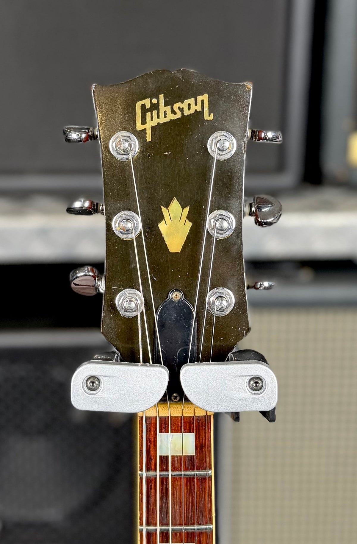 Close-up of the front of the Gibson SG Deluxe headstock showing the Gibson logo and crown inlay above the six tuners.