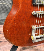 Close-up of the lower cutaway horn of the Gibson SG Deluxe showing chipped and worn finish along the edge, exposing bare wood in places.