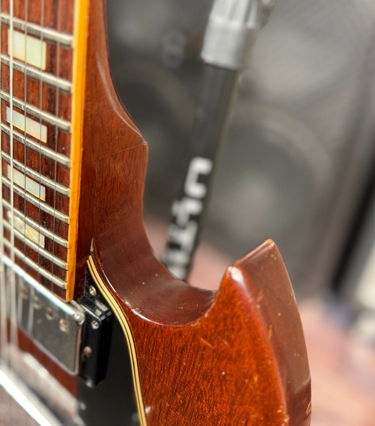 Close-up of the neck heel where it joins the body on the Gibson SG Deluxe, showing the cream body binding along the edge.