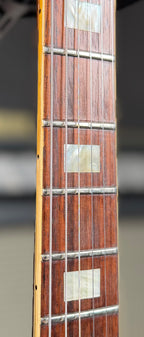 Close-up of the rosewood fretboard on the Gibson SG Deluxe, showing the trapezoid position markers and frets.