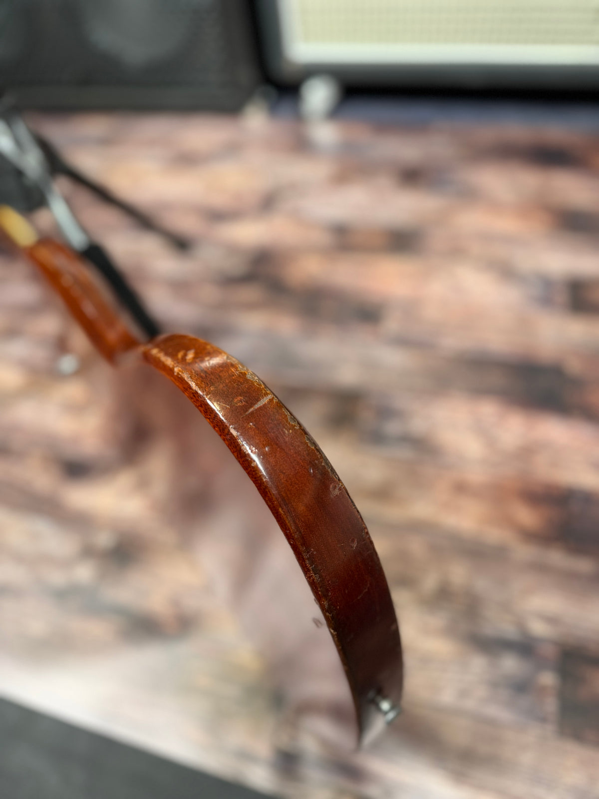 Close-up of the Gibson SG Deluxe's body edge, resting on a stand, showing worn and scuffed finish along the curve.