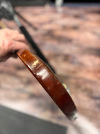 Extreme close-up of the Gibson SG Deluxe's body edge, held in a hand, showing scuffed and worn finish along the curve.