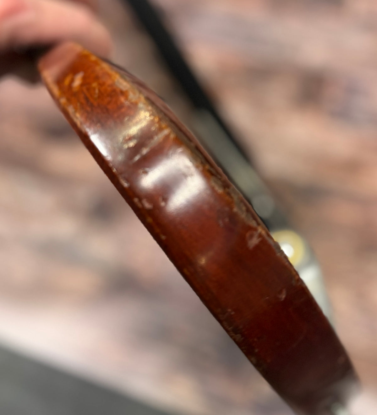 Extreme close-up of the Gibson SG Deluxe's body edge, held in a hand, showing worn and scuffed finish.