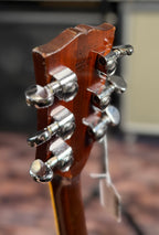 Close-up of the back of the Gibson SG Deluxe headstock from a different angle, showing the serial number, 'Made In USA' stamp, tuners and a small hang tag.