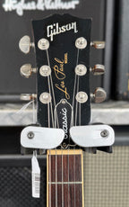 Close-up of the black Gibson Les Paul Classic headstock showing the pearl logo lettering, nickel tuners and a price tag hanging from the strings.