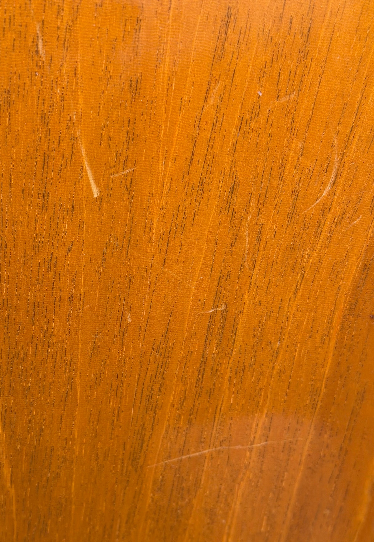 Extreme close-up of the mahogany back finish showing several fine surface scratches and light handling marks.