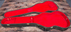 Open Gibson hardcase interior with worn red plush lining, shown empty without the guitar inside.