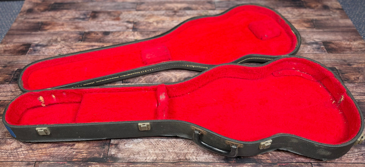 Open Gibson hardcase interior with worn red plush lining, shown empty without the guitar inside.